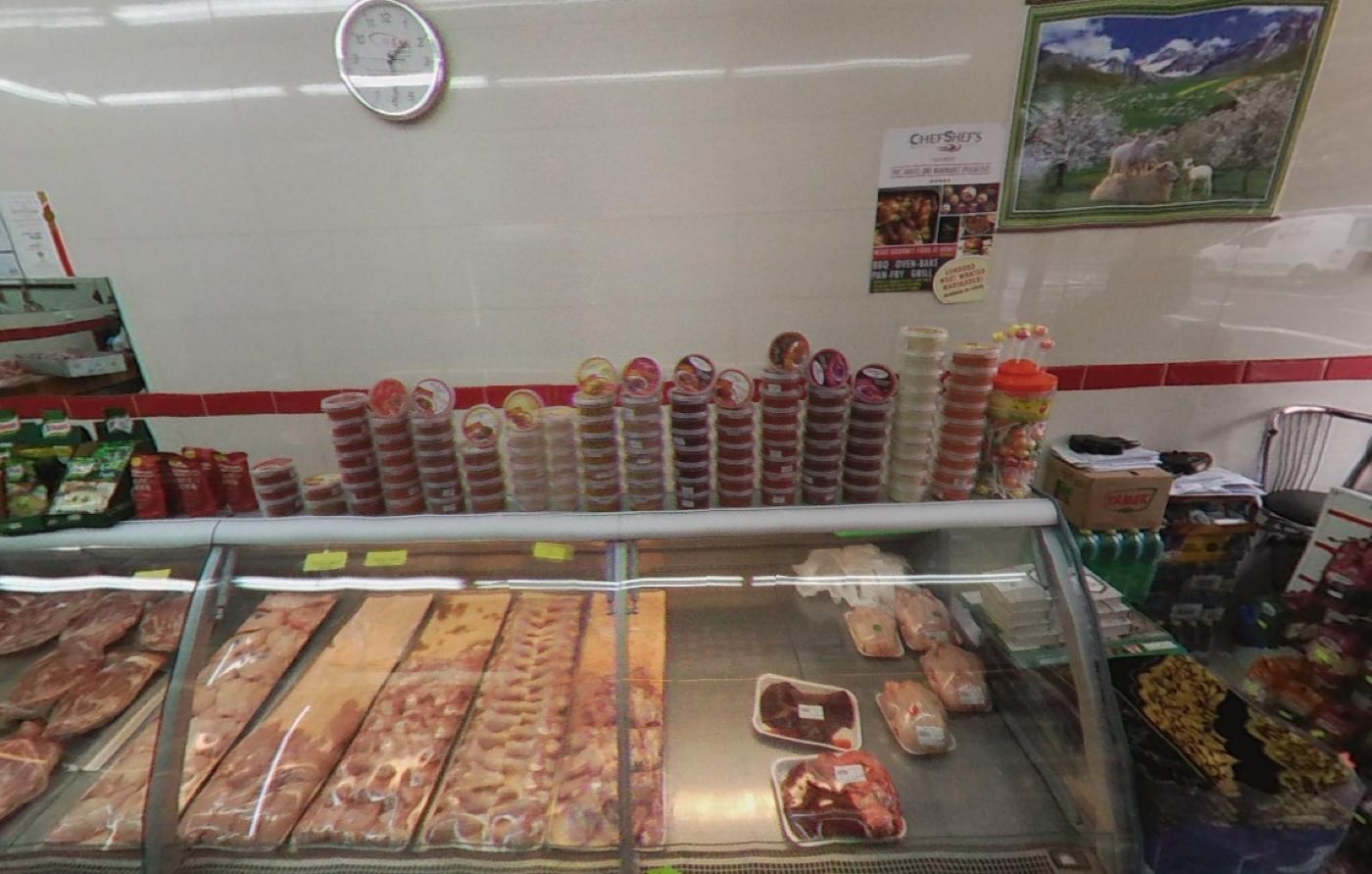 Rows of marinated meats in tubs above the counter at Super Butcher, with trays of fresh chicken in the case below.